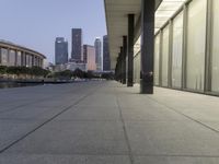 the walkway at the park leads to a lake and buildings in the background as evening falls