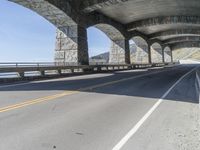 a car is driving down the road next to an overpass with some columns near it