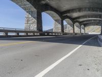 a car is driving down the road next to an overpass with some columns near it