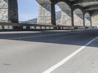 a car is driving down the road next to an overpass with some columns near it