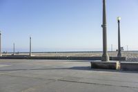 the parking lot on a city beach has a concrete bench at the corner with several streetlights