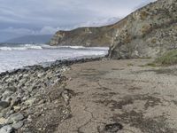 a large cliff that is sticking out over the water and rocky shore by it's banks