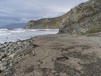 a large cliff that is sticking out over the water and rocky shore by it's banks