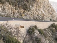 a person riding on the back of a motorcycle down a winding road next to some cliffs