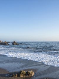 a grassy field by the shore and a cliff with rocks in the ocean in the background