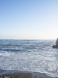 a grassy field by the shore and a cliff with rocks in the ocean in the background