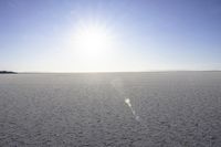 the sun is setting on a snowy plain with no cars in the image while the sky is blue