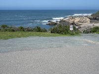 an empty parking lot near the ocean with a sign in the foreground reading no parking and beach next to them