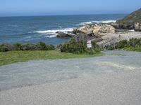 an empty parking lot near the ocean with a sign in the foreground reading no parking and beach next to them