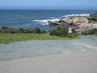 an empty parking lot near the ocean with a sign in the foreground reading no parking and beach next to them