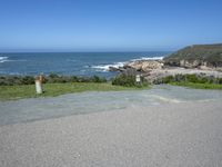 an empty parking lot near the ocean with a sign in the foreground reading no parking and beach next to them