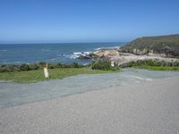 an empty parking lot near the ocean with a sign in the foreground reading no parking and beach next to them