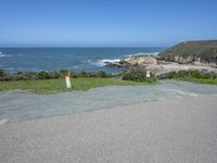 an empty parking lot near the ocean with a sign in the foreground reading no parking and beach next to them