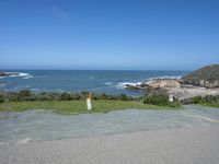 an empty parking lot near the ocean with a sign in the foreground reading no parking and beach next to them