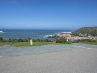 an empty parking lot near the ocean with a sign in the foreground reading no parking and beach next to them