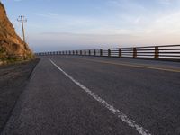 a motorcycle driving across an empty highway near mountains on a sunny day in the fall