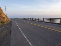 a motorcycle driving across an empty highway near mountains on a sunny day in the fall