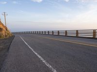 a motorcycle driving across an empty highway near mountains on a sunny day in the fall