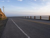 a motorcycle driving across an empty highway near mountains on a sunny day in the fall