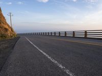 a motorcycle driving across an empty highway near mountains on a sunny day in the fall