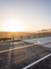 a truck is driving on the highway next to a field at sunset time and it appears like going over a bridge