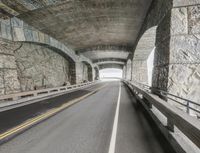 a empty highway under an overpass leading to some large rocks and beams and a bridge