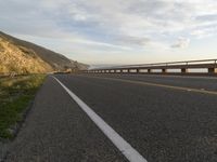 a bike is traveling along the road to a rocky beach side cliff area below it