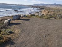 an empty spot is sitting by the beach next to the water and mountains that surround