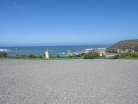 a fire hydrant on a grassy hillside near a ocean bank with surf and rocks