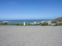 a fire hydrant on a grassy hillside near a ocean bank with surf and rocks