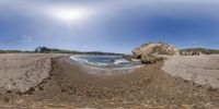 a view of the water on the beach from a fish eye lens of rocks and water