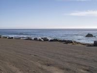 there is a motorcycle that is standing by the shore next to the water and rocks