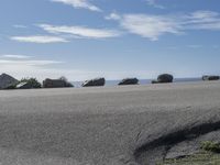 a man rides a motor bike down the road on the beach with rocks in the background