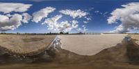 a reflection of the sky and ground in a panoramic shot of some rocks and sand