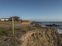 a grassy field by the shore and a cliff with rocks in the ocean in the background