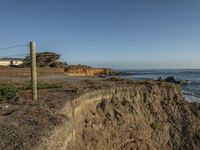 a grassy field by the shore and a cliff with rocks in the ocean in the background