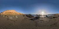 a rock outcropping in the sand with a bright sun reflecting off of it