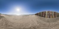 a fish - eye view of the sand and the beach, with wooden fences surrounding it