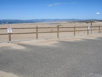 a paved beach with a fence in front of it and the ocean in the distance