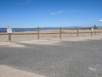 a paved beach with a fence in front of it and the ocean in the distance