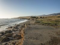 a grassy field by the shore and a cliff with rocks in the ocean in the background