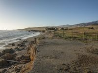 a grassy field by the shore and a cliff with rocks in the ocean in the background