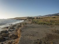 a grassy field by the shore and a cliff with rocks in the ocean in the background