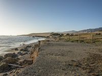 a grassy field by the shore and a cliff with rocks in the ocean in the background