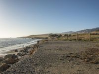 a grassy field by the shore and a cliff with rocks in the ocean in the background