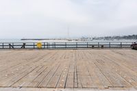 the wooden floor of a pier with a yellow surf board in the water behind it