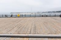 the wooden floor of a pier with a yellow surf board in the water behind it