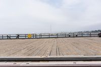 the wooden floor of a pier with a yellow surf board in the water behind it