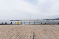 the wooden floor of a pier with a yellow surf board in the water behind it