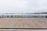 the wooden floor of a pier with a yellow surf board in the water behind it